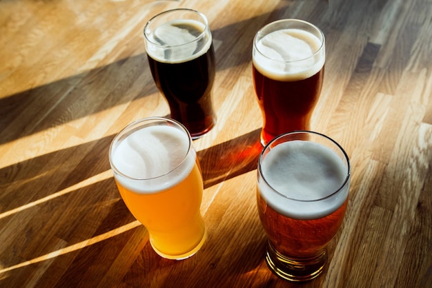 Foto quatro copos de cerveja em uma mesa de madeira