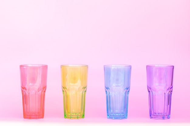 Foto quatro copos de vidro idênticos: vermelho, verde, azul, roxo.