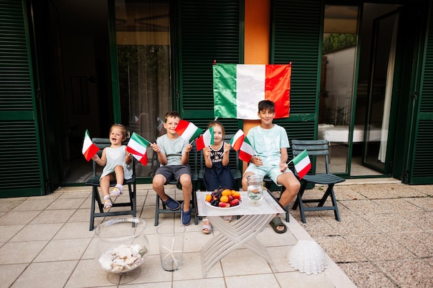 Quatro crianças felizes com bandeiras italianas comemorando o Dia da República da Itália