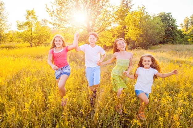 Quatro crianças lindas e felizes correndo, brincando, movendo-se juntas no lindo dia de verão