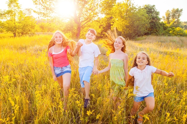 Quatro crianças lindas e felizes correndo, brincando, movendo-se juntas no lindo dia de verão