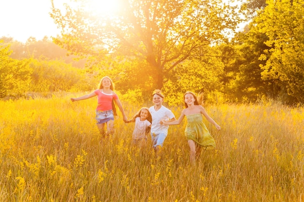 Quatro crianças lindas e felizes correndo, brincando, movendo-se juntas no lindo dia de verão