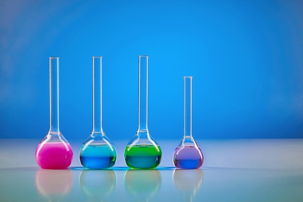 Quatro frascos médicos com reagentes químicos coloridos para testes fundo azul Pesquisa laboratorial de Coronavirus Pandemia mundial COVID19 2019nCoV SARSCoV2 Doença infecciosa Fechar