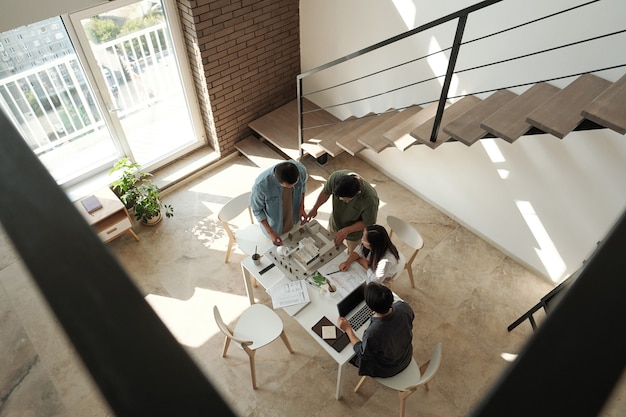 Quatro jovens arquitetos chineses discutindo o layout da casa