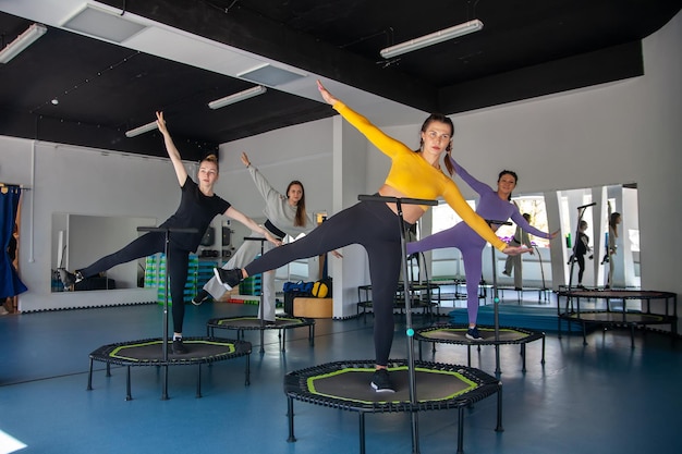 Quatro jovens mulheres no trampolim jovens fitness treinam no estúdio de fitness