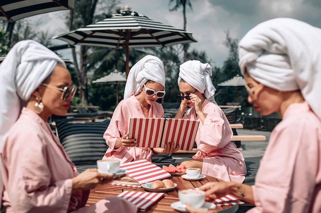 Quatro lindos adultos e modelos fofos vestindo as mesmas roupas, descansando em um café e decidindo o que pedir. Conceito ao ar livre