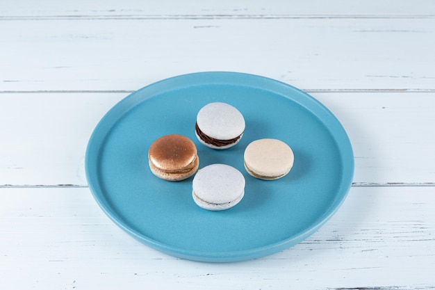 Quatro macarons recheados com ganache de chocolate e doce de leite em um prato azul