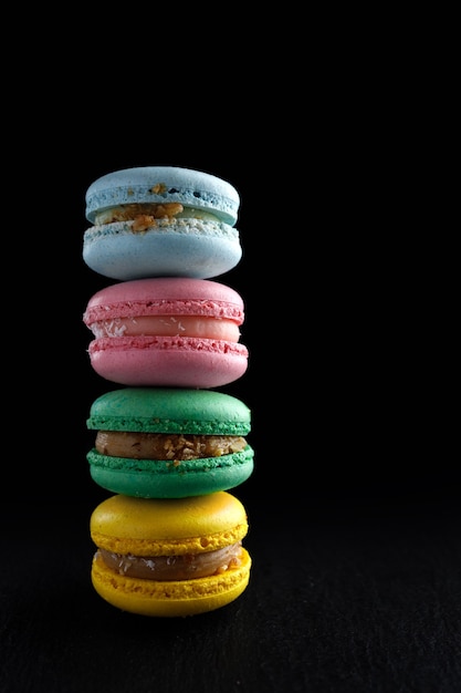 Quatro macaroon de produtos naturais caseiros multicoloridos em um fundo preto