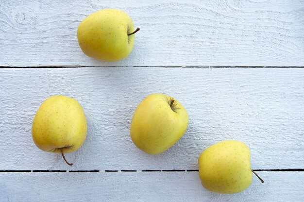 quatro maçãs douradas em um fundo branco de madeira