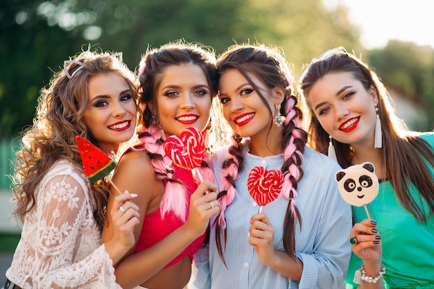 Quatro melhores amigas posando com velas na vara e sorrindo.