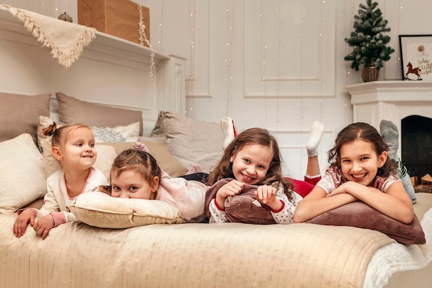 Quatro meninas na cama no fundo da árvore de Natal e enfeites