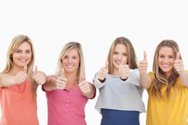 Quatro meninas sorridentes dando o polegar para cima