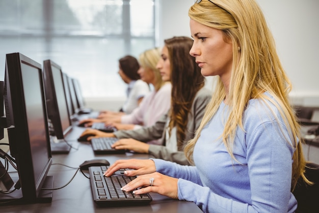 Quatro mulheres focadas trabalhando na sala de computadores