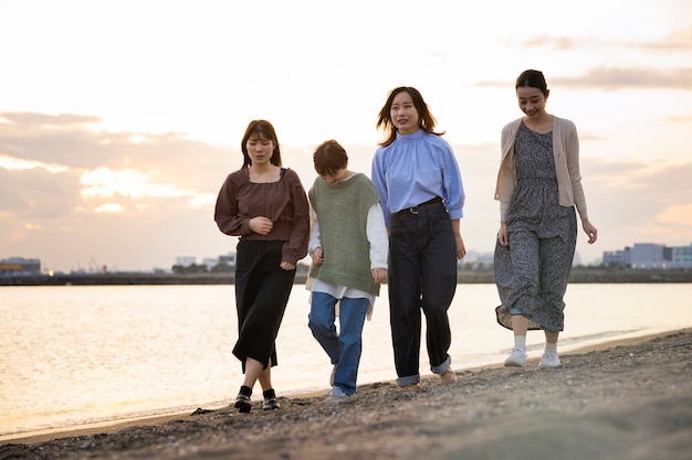 Quatro mulheres jovens caminhando à beira-mar ao anoitecer