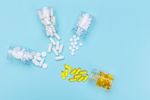 Quatro pacotes com várias pílulas brancas e cápsulas em um fundo branco