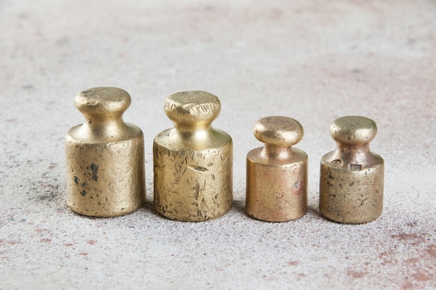 Quatro pesos de bronze antigos para escalas em fundo de concreto. Copie o espaço para adereços de fotografia de texto e comida.