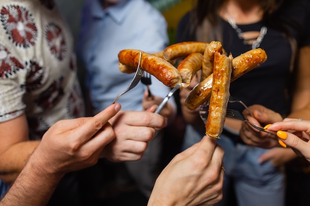 Quatro pessoas seguram um cachorro-quente juntas.