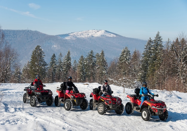 Quatro pilotos de atv em quadriciclos off-road no topo da montanha no inverno