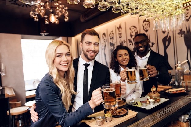 Quatro rapazes e raparigas pediram uma cerveja no bar.