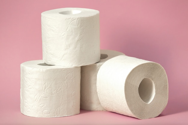 Quatro rolos de papel higiênico branco ficar em um fundo rosa