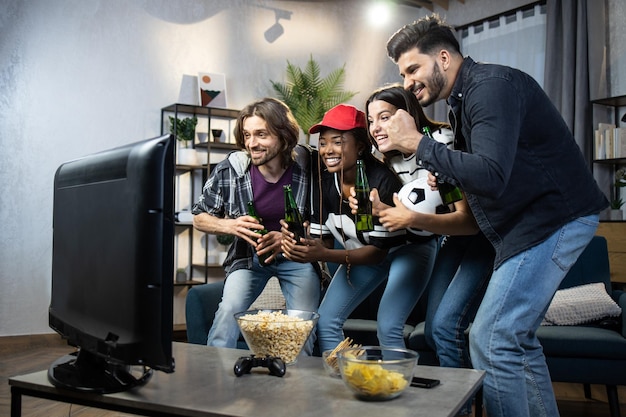 Quatro torcedores multirraciais emocionados torcendo pelo time de futebol