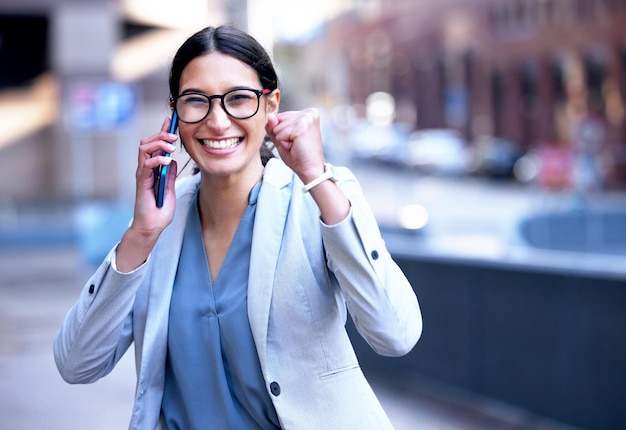 Qué bondad me esperaba Foto de una joven empresaria vitoreando de felicidad durante una llamada telefónica