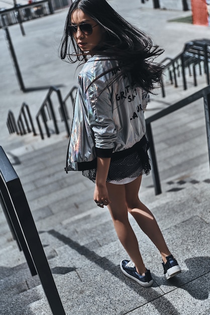 Que buen look. Vista trasera de longitud completa de hermosa mujer joven en ropa casual mirando por encima del hombro