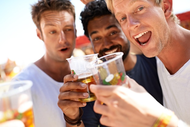 Que comece a festa. Três jovens brindando suas cervejas em um festival de música.