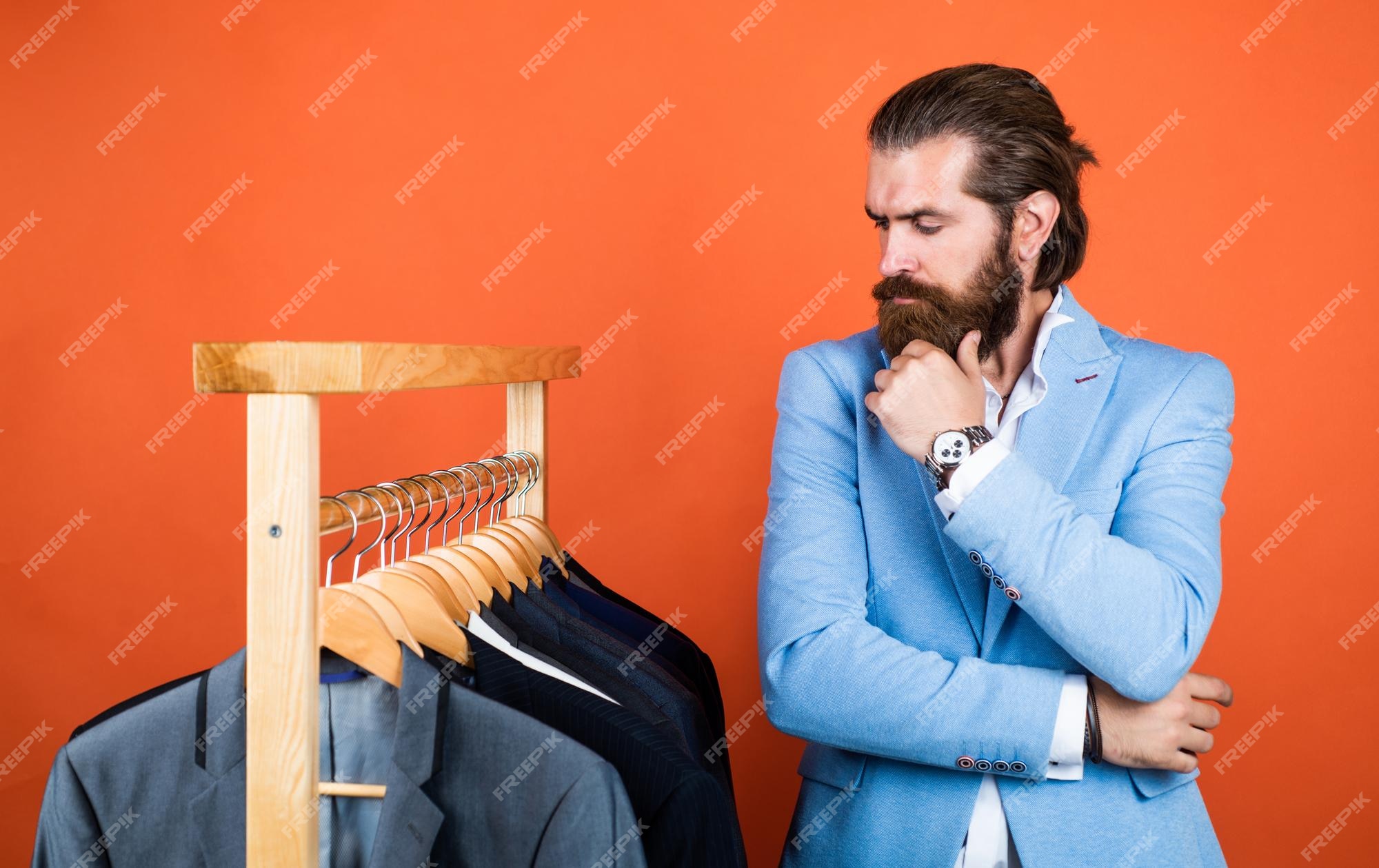 Qué elegir hombre guapo con ropa informal elegante mirando trajes y eligiendo ropa de hombre con estilo en el puesto de perchas en la habitación de moda de negocios estilo servicio de en seco y concepto de | Foto Premium