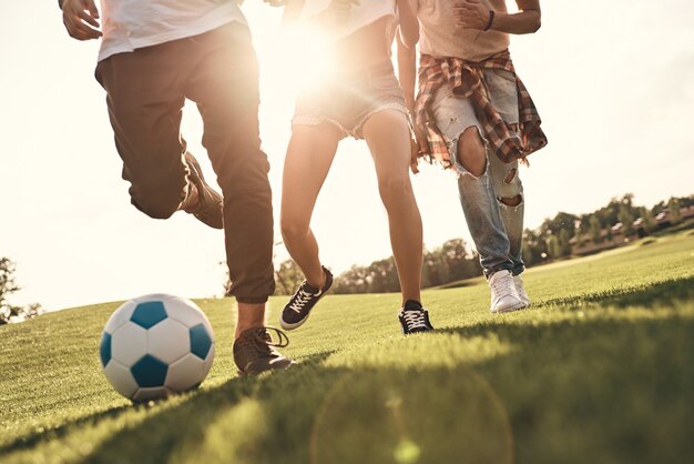 ¡Que empiece el juego! Primer plano de los jóvenes en ropa casual corriendo mientras juegan al fútbol al aire libre