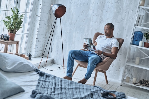 ¿Qué hay de nuevo en el mundo? Hombre africano joven guapo leyendo el periódico
