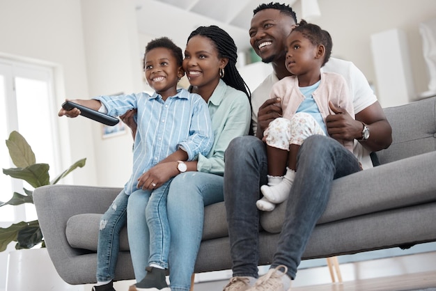 ¿Qué hay en la tele? Toma en ángulo bajo de una afectuosa familia joven de cuatro personas viendo la televisión en la sala de estar de su casa.