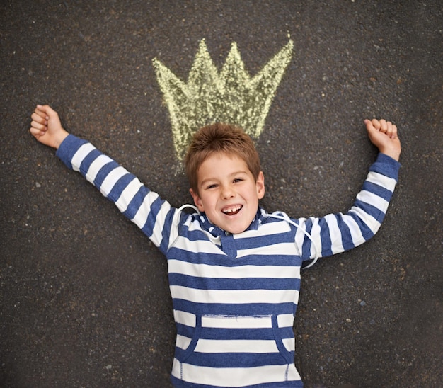 Qué lindo príncipe Un niño tirado en el suelo y sonriendo a la cámara