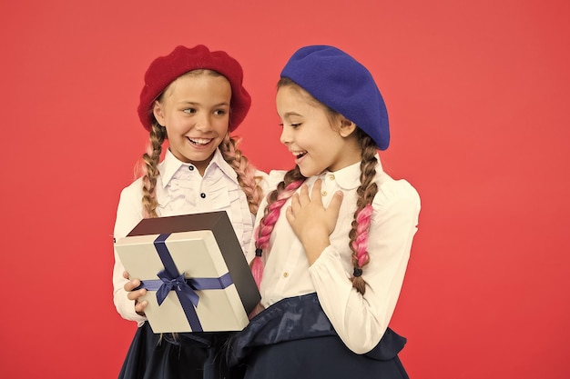 Qué maravillosa sorpresa Niños felices con una pequeña caja de regalo envuelta con un lazo de cinta Niña dando un regalo a un amigo Niños pequeños disfrutando de la celebración navideña Sorpresa de cumpleaños Feliz cumpleaños