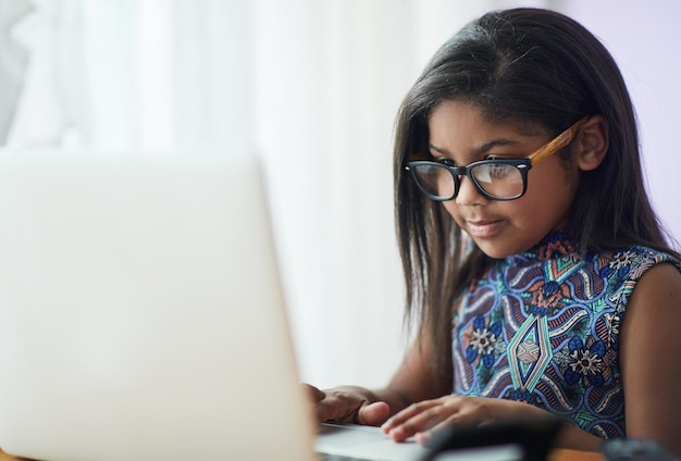 ¿Por qué pagar el franqueo cuando puedes enviar un correo electrónico a la abuela? Foto de una linda niña usando una computadora portátil en su dormitorio en casa