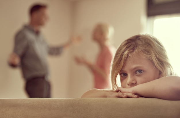 Foto ¿por qué tienen que pelear? la foto de una niña que parece infeliz mientras sus padres discuten en el fondo.