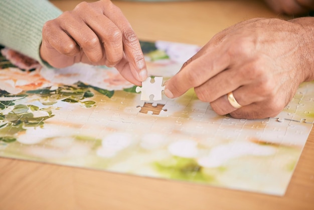 Foto quebra-cabeça na peça de mesa e nas mãos do casal em casa para unir atividades divertidas e relaxar juntos casamento de aposentadoria e close de pessoas com quebra-cabeças para jogar jogos, hobby e entretenimento