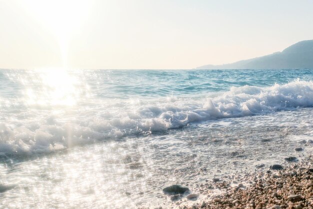 Quebrando a onda do oceano azul na praia de seixos, fundo de verão