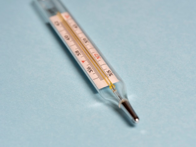 Quecksilberthermometer auf blauem Hintergrund, Nahaufnahme, selektiver Fokus. Werkzeug zum Ändern der Temperatur von Patienten