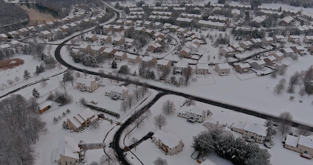 Queda de neve sobre uma pequena cidade residencial com casas de telhados cobertos de neve na antena de inverno rural dos eua