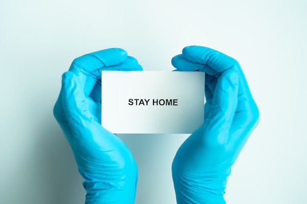Quédese en casa y saludable para evitar la campaña de propagación de covid-19, texto en papel con las manos del médico en forma de corazón con guantes azules