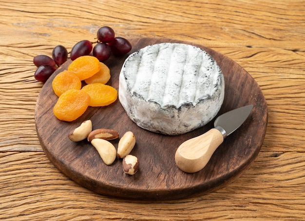 Queijo artesanal brasileiro Lua Cheia com frutas e nozes sobre mesa de madeira