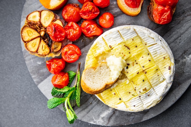 Queijo assado Brie ou Camembert com tomate, alho e ervas refeição saudável lanche na mesa