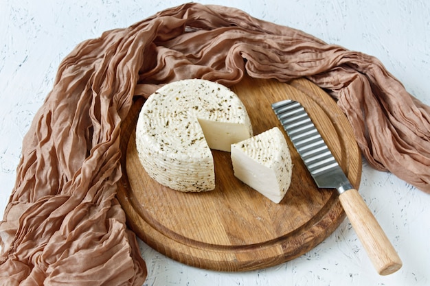 Queijo branco em uma placa de madeira sobre um fundo branco