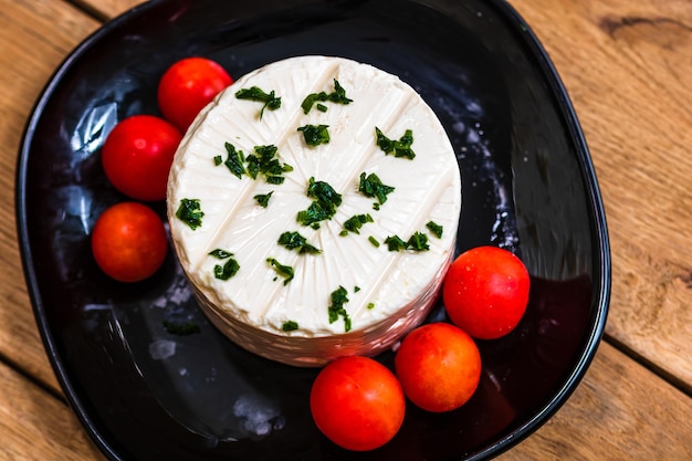 Foto queijo branco saboroso com especiarias e tomates cherry na tábua de cortar