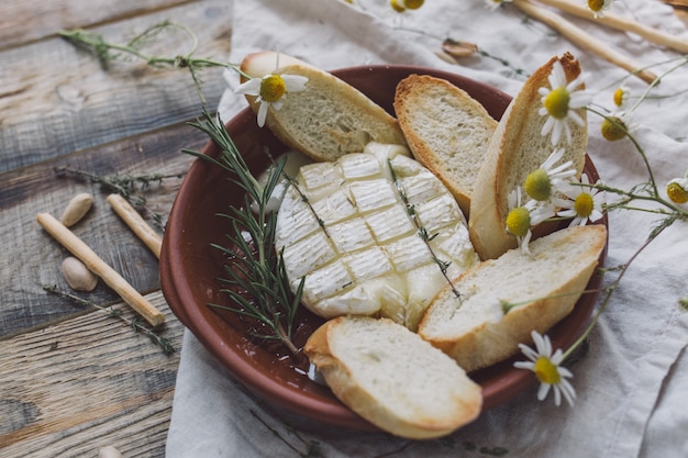 Queijo brie assado com torrada de pão em um prato de barro.