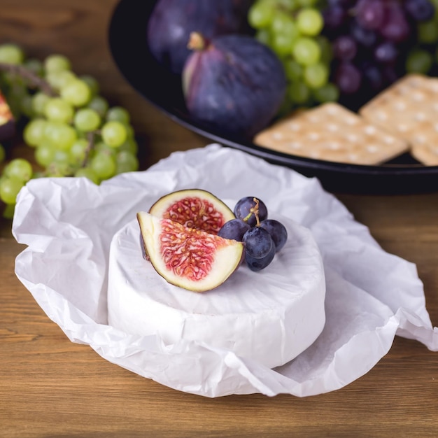 Queijo Brie Camembert com Figos e Uvas na mesa de madeira Comida para Vinho Figos Uvas Verdes e Vermelhas Biscoitos Faca Prato Petiscos Quadrado