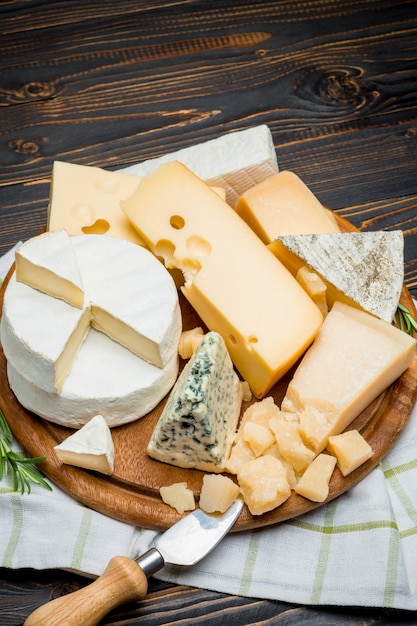 queijo brie, camembert, roquefort e queijo cheddar na placa de madeira