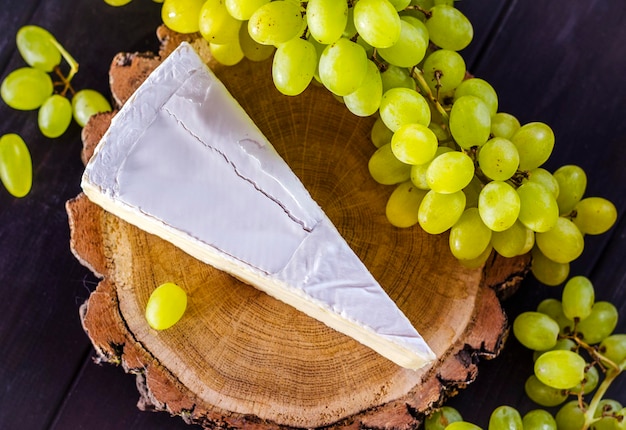 Queijo brie e uvas frescas brancas em uma placa de madeira