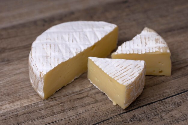 Queijo brie redondo com uma seção cortada sobre fundo de madeira, vista de perto